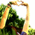 Two people in a grassy field form heart shapes with their hands, one person jumps while another holds a child.