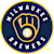 Circular icon with blue background, yellow border, and white star-like shapes around the perimeter, featuring a central golden emblem with a bright white center.