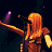 Pixelated image of a female musician with long orange hair singing into a microphone on stage, next to green text reading "Original Icons .com" on a dark background.