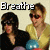 Two people sit side-by-side; one wears a black top and dark sunglasses, the other yellow shirt and red-tinted sunglasses with blue balloons. Text "Breathe" appears above left.