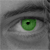 A static close-up of a human eye with green iris and black pupil, set against grayscale skin tones and dark eyelashes.