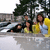 Pixelated static image shows three figures near water with trees in background; one figure in yellow shirt, another in dark clothing, third in light blue shirt.