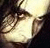 A pixelated close-up of a person's face with dark hair, partially obscured by shadows and light tones.