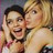 Two people in close physical proximity, one with dark hair and the other with light blonde hair, both smiling broadly.