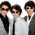 Three people in suits with sunglasses on a white background, and a peace symbol drawn in sand with the word 'peace' below it.