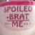 A static icon with pixelated text reading "SPOILED BRAT ME" in red letters on a light background, featuring small brown dots and lines as decorative elements.