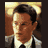 Static pixelated image of a man's face and upper torso in formal attire with warm lighting, likely from a movie scene.