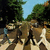 Pixelated outdoor scene with two figures walking on a path under trees, blue sky visible above.