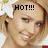Pixelated close-up of a person with light brown hair, wearing a red garment and holding an object near their face.