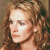Pixelated close-up of a person with light brown curly hair, fair skin, and a neutral expression against a muted brown background.