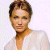 Pixelated portrait of a person with short brown hair wearing a white top against a light background.