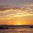 A static image with a sunset beach scene on the left and red background with pixelated text on the right.