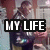 A static image shows a person in dark clothing holding an object, with "MY LIFE" text overlaid on a black rectangle.