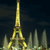 Pixelated nighttime view of a golden Eiffel Tower with surrounding smaller structures against a dark sky.
