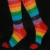 Pixelated rainbow-colored legs and feet on a black background, with gradient transitions between red orange yellow green blue purple hues.