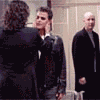 Six- of a man in a black suit standing in a hallway with a woman in a black suit, text overlays change