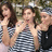 Three people in a group pose with arms raised, wearing striped and dark clothing against a blurred background.