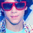 A pixelated image of a person with blue hair wearing red sunglasses and a checkered shirt, with another person in an orange and white striped shirt in the background.