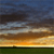 A static pixelated image depicting a sunset or sunrise over a horizon with layered clouds and a dark ground strip.