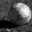 A grayscale pixelated image shows a large spherical object with a bright highlight on its right side, set against a dark textured background with a solid black horizontal band at the bottom.