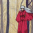 Pixelated static image of a character in red clothing with silver helmet-like headgear against vertical striped background.