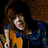 Six show a person with brown hair in various poses: playing guitar, making a peace sign, blowing pink bubblegum, holding a cat, wearing a dark blue shirt with yellow accents, and holding a purple patterned item