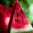 A watermelon slice with red flesh, black seeds, and green rind appears in a