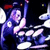 Pixelated animated contact sheet showing two drummers in dark clothing with red headgear playing drums under blue lighting against a black background.