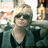 Pixelated static image of a person with light hair wearing dark sunglasses and a black top, set against an indistinct background.