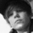 Black-and-white pixelated image of a person's face with dark hair, closed eyes, and a neutral expression, cropped to show only the upper head and shoulders.