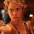 A pixelated image of a woman with short blonde hair in an indoor setting, wearing a black strap top and green shoulder straps.