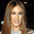 Pixelated image of a person with long brown hair wearing a light-colored top against a dark background with small colored pixels.