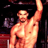 Two side-by-side pixelated frames of a shirtless muscular man with dark skin and short hair, one raising his right arm upward against a black background.