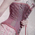 A person in a maroon sleeveless top and white patterned skirt holds a red cane, with a handbag visible over the shoulder.