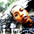 Pixelated image of a person with light skin and brown hair lying down, wearing a dark top with a pink detail, against a blurred background with green and blue tones.