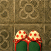 Two green gift boxes with red ribbons and white polka dots sit against a stone tile background with floral patterns.