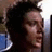 A person with dark hair in profile view, showing three sequential facial expressions against a blurred background.