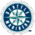 Circular icon with white border, dark blue background, and teal cross dividing four quadrants of white shapes resembling stylized letters or symbols.