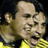 Pixelated static image of a bald man with light skin wearing a yellow shirt, visible from the shoulders up against a dark background.
