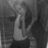 A grayscale pixelated image of a person holding an object near their face, with indistinct background elements.