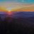 Pixelated horizontal bands of color transition from teal and gray at the top through yellow and orange to deep purple and black at the bottom.