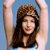 A pixelated image of a person with long brown hair wearing a dark top, arms raised against a solid blue background.
