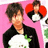 Pixelated image of two figures against pink background; one figure wears black jacket with green accents, the other has red hair and white clothing.