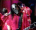 Animated sequence of a person in red clothing playing an electric guitar against a dark background with purple curtains.