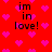 Red background with pink pixelated hearts and black text reading "im in love!" repeated four times.