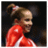 A gymnast in a red and white leotard with hair tied up, positioned next to a of six red squares containing white letters spelling 'Cayley' on a gray background