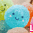 A pixelated blue circular character with a smiling face appears in a of repeated green and orange shapes, with text below changing across frames