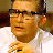 Pixelated static image of a person wearing glasses and a white shirt with visible hands in motion, set against a blurred background.