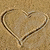 A heart drawn in sand, a colorful piano keyboard, and a blue starfish on a light surface.
