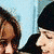 A pixelated image of a person with long brown hair wearing a black top and white ruffled collar, partially cropped on the left side.